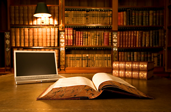 Lawbook opened with labtop and bookshelf in background